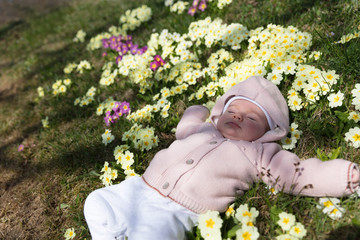 Newbown baby girl having afteroon nap lying in the garden blossom