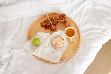 Tray with tasty breakfast on bed