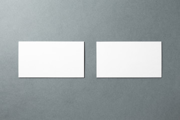 White blank business cards neatly stacked on a gray background. Composition of two cards for layout design. Front and back view.