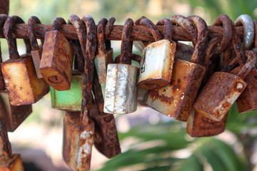Rusty lovers lock hangs on a metal cable at Chanthaburi , Many old rusty metal locks closed.