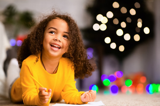 Dreamy african child writing wishlist for Christmas holidays
