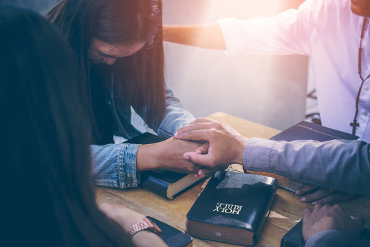 Group of Christians are congregants join hands to pray and seek the blessings of God, the Holy Bible. The cross symbol. They were reading the Bible and sharing the gospel with copy space.