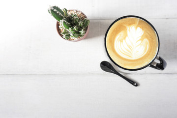 Hot cappucino on white wood background with cactus.