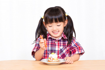Naklejka premium 白背景でおやつのケーキを楽しそうに食べる幼い女の子。幸せ、成長、健康イメージ