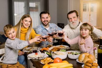 Family Together Dinner Celebration Concept, Thanksgiving holiday. Happy smiling family sitting at the table and enjoying time together, having tasty dinner, holding glasses with wine and juice