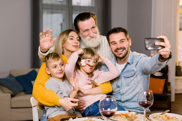 Portrait of happy multi generation family taking selfie photo sitting at dinner table while celebrating holidays. thanksgiving day, birthday party