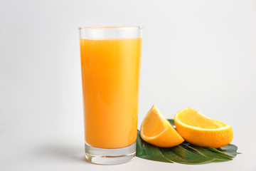 Glass of fresh orange juice on light background
