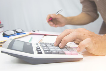 businessman using calculator and holding pen on tax paper in office.Accounting.concept.