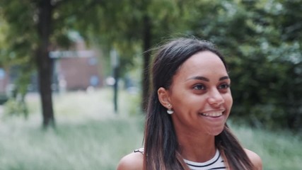 Close-up of african girl closing boyfriend's eyes. Surprised man taking her in his arms and kissing. They having date outdoors.