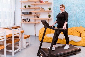 Fototapeta na wymiar Model - a fat woman, trying to lose weight and at home engaged on a treadmill.