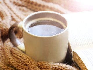 A Cup of hot coffee and a beige warm scarf