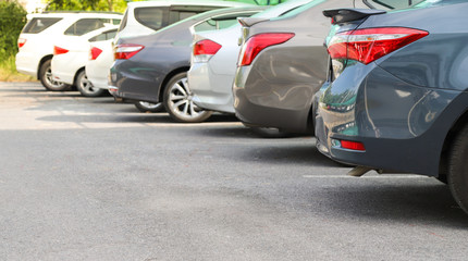 Closeup of rear, back side of blue car with  other cars parking in outdoor parking area in bright sunny day. 