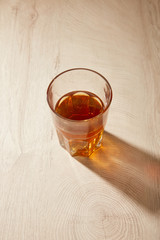 glass of fresh beer on wooden beige surface with shadow