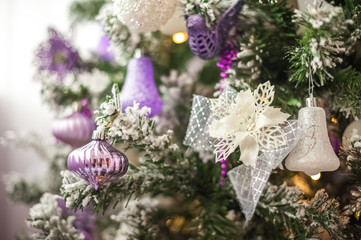 Background from a Christmas tree decorated in blue and purple close-up. Greeting card from a Christmas tree with purple decorations and copy space.