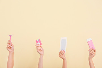 Female hands with supplies for hair removing on color background