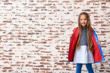 Obraz na płótnie Canvas Fashionable little girl in autumn clothes near brick wall