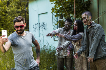 Naklejka premium Selfie on a background of zombies, zombies tied to an abandoned house