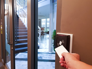 Men hand reaching to use RFID key card to access the area. In building security only for authorized...