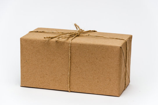 Single box wrapped with brown kraft paper and tied with twine on a white background. Delivery, moving, package and gifts concept. Copy space