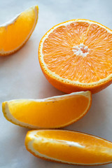 Close-up half of orange and slice on light table surface. Fresh citrus fruit, vertical composition