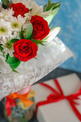 Beautiful bouquet of roses with chrysanthemums and a box with a gift.