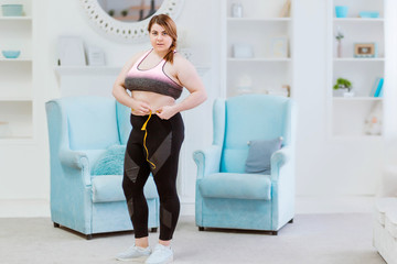 Model - fat woman, measuring the size of the waist with a measuring tape