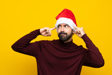 Fototapeta premium Man with christmas hat over isolated yellow background having doubts and thinking