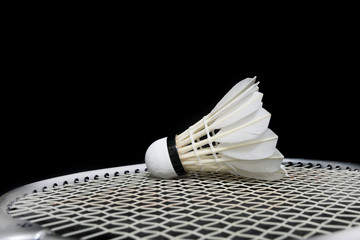 Badminton shuttlecock and racket on grass and black background