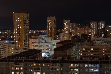 Fototapeta na wymiar Residential areas on a winter night. Glowing windows of multi-storey residential buildings. A lot of parked cars in the yards