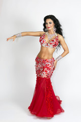 Brunette beautiful long red dress to perform belly dance on a white background