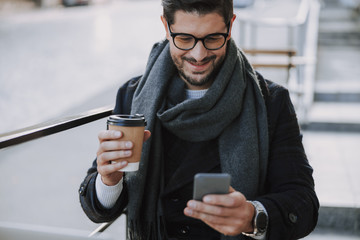 Smiling good-looking man in eyeglasses typing message