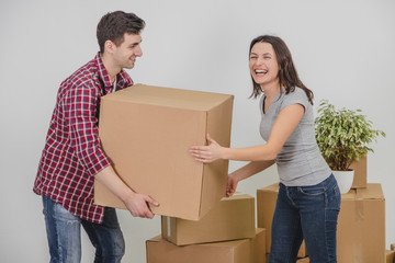 Couple in a new flat. Young man is totaly exhausted. He can not hold heavy box anymore, he almost dropped it, but woman helped him.