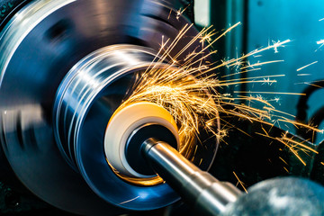 Sparks fly from an abrasive stone on a grinding machine. - obrazy, fototapety, plakaty
