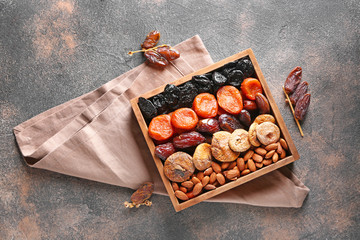 Box with different dried fruits and nuts on grey background
