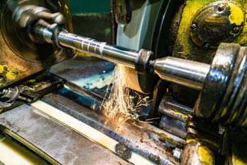Grinding a shaft on a circular grinding machine with an abrasive stone.