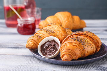 Plate with tasty sweet croissants and chocolate on table