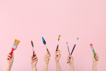 Female hands with painter's supplies on color background