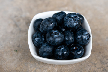 Freshly picked blueberries in white bowl. Juicy and fresh. Bilberry on cement background. Blueberry antioxidant for healthy eating and nutrition.