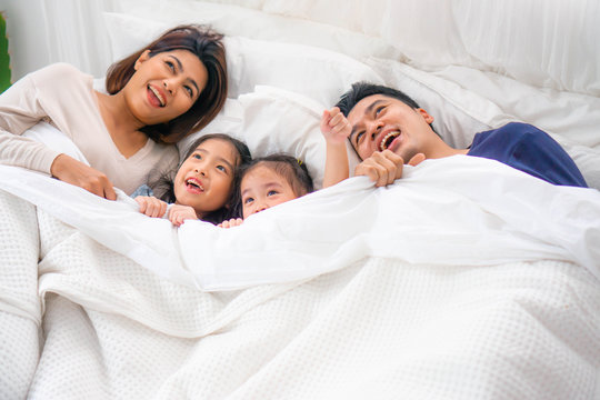Asian happy family play together on bed