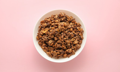 Bowl with tasty granola on color background