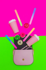 Fashion set of open pastel pink handbag, donuts and cups of coffee on fuchsia and bright neon green background