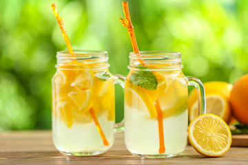 Mason jars of fresh lemonade on wooden table outdoors