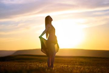 Silhouette of a beautiful girl in a light dress at sunset in the mountains.