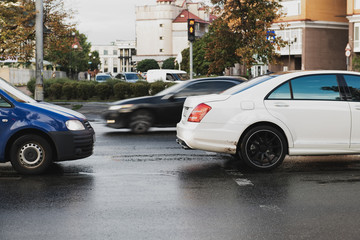 Two cars on the pedestrian crossing in the city. Traffic violation concept photo. White car on rainy day. Keep the distance. Before the crash. Intruder on the road.