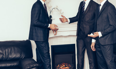 three businessmen discussing a deal, standing in the meeting room