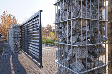 Gabion. Automatic entrance gate used in combination with a wall made of gabion.