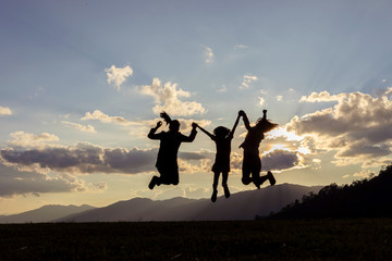 family silhouette jumping with raised arms at sunset. Backlight shot. success, friendship and community concepts.