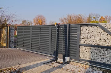 Fotobehang Gabion. Automatic entrance gate used in combination with a wall made of gabion. © Wlodzimierz