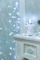 Gentle sky blue Christmas background with bokeh and burning candle in the foreground standing on the table. Christmas winter vintage background. The Concept Of A Happy Christmas.
