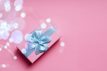 Gift box with Blue ribbon on Pink background for copy space. Christmas minimal concept idea.